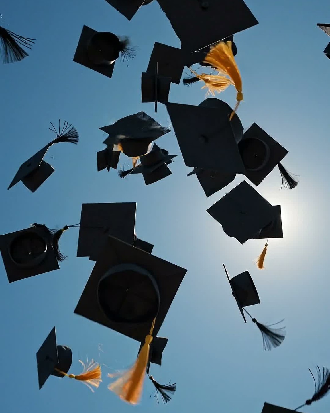 Graduation caps thrown against a bright blue sky